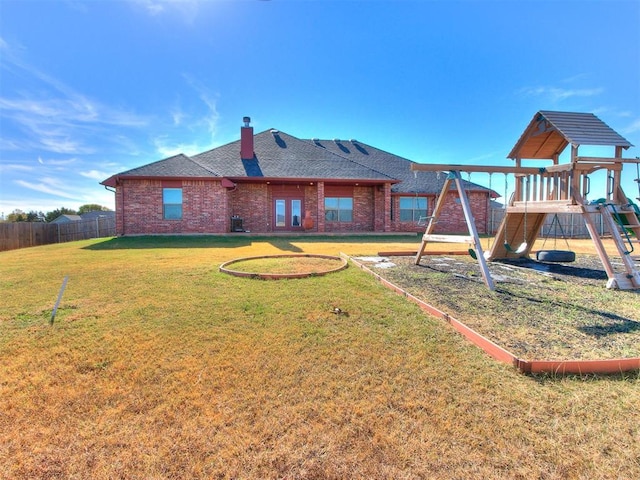 back of house featuring a playground and a yard