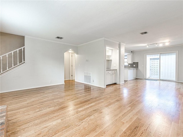 unfurnished living room with ornamental molding and light wood-type flooring