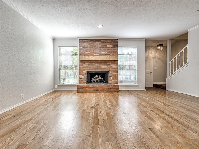 unfurnished living room featuring light hardwood / wood-style flooring, a textured ceiling, and ornamental molding