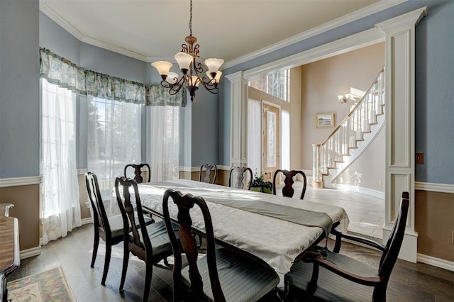 dining space featuring a chandelier, light wood-type flooring, decorative columns, and ornamental molding