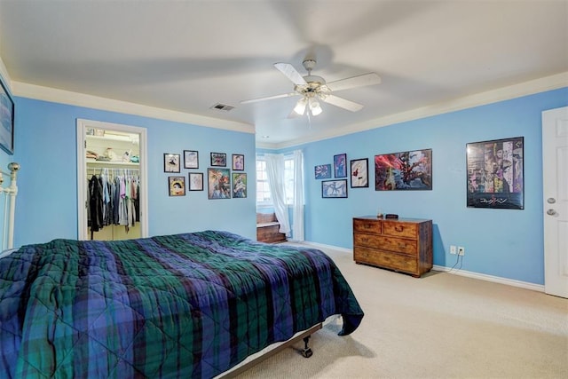 carpeted bedroom featuring a walk in closet, ceiling fan, a closet, and crown molding