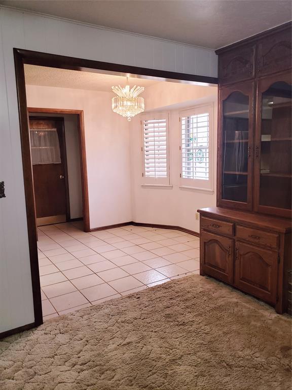 unfurnished dining area featuring light tile patterned flooring and an inviting chandelier