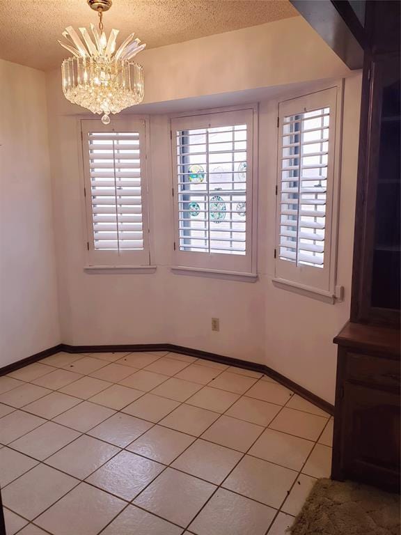 unfurnished room featuring light tile patterned floors, a textured ceiling, and an inviting chandelier