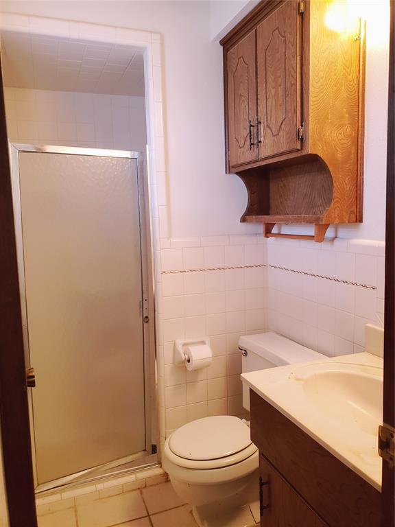 bathroom featuring vanity, a shower with door, and tile walls