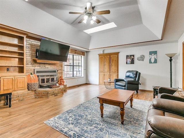 living room with a skylight, light hardwood / wood-style floors, and ceiling fan