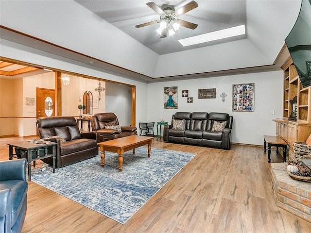 living room featuring hardwood / wood-style flooring, ceiling fan, a raised ceiling, and a skylight