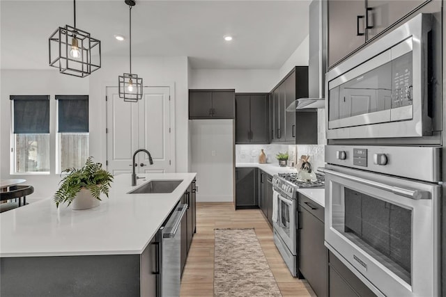 kitchen with light hardwood / wood-style floors, a center island with sink, stainless steel appliances, and sink