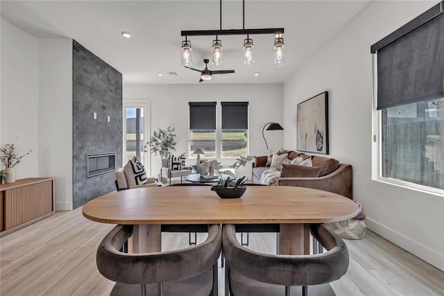 dining room with a large fireplace and light hardwood / wood-style floors