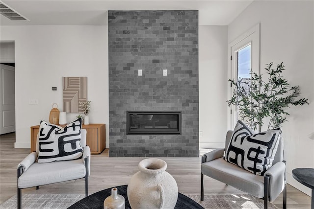 living room featuring light wood-type flooring and a tiled fireplace