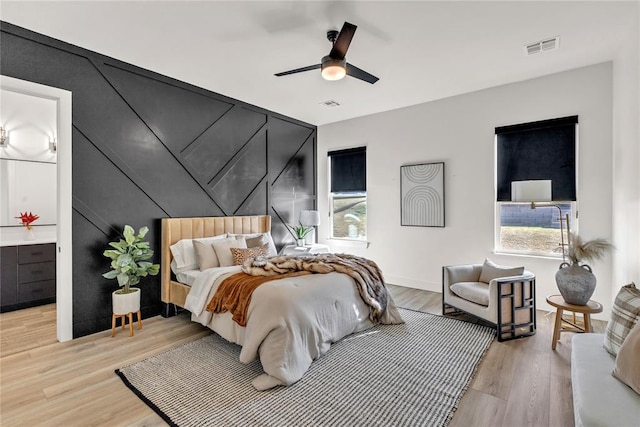 bedroom featuring ceiling fan, light hardwood / wood-style flooring, and multiple windows