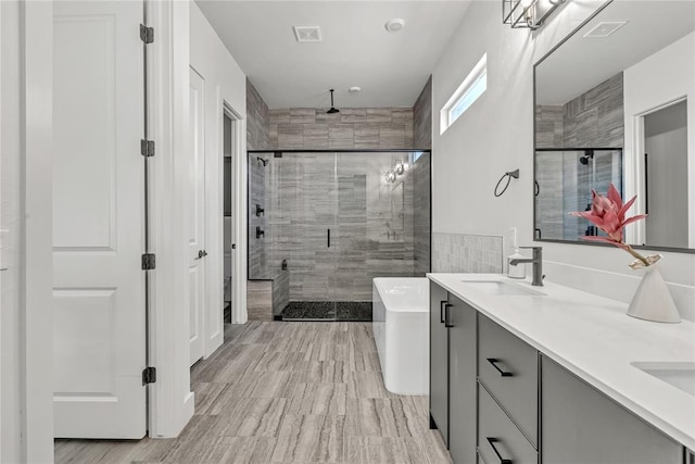 bathroom featuring plus walk in shower, hardwood / wood-style floors, and vanity