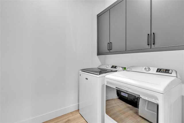 clothes washing area featuring light hardwood / wood-style floors, cabinets, and independent washer and dryer