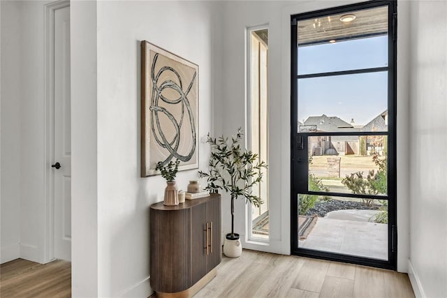 entryway with baseboards, plenty of natural light, and light wood finished floors