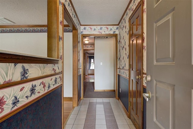 hall featuring crown molding, light colored carpet, and a textured ceiling