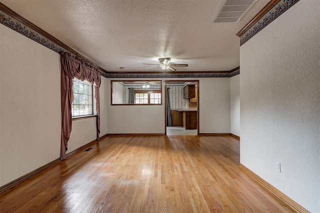 unfurnished room featuring a textured ceiling, light wood-type flooring, ceiling fan, and ornamental molding