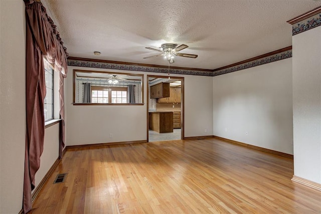 unfurnished room with ceiling fan, crown molding, a textured ceiling, and light hardwood / wood-style flooring