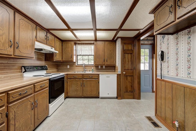 kitchen featuring wood walls, sink, white appliances, and a textured ceiling