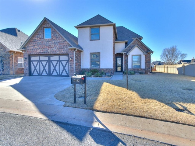 view of front of property with brick siding, stucco siding, concrete driveway, fence, and a garage