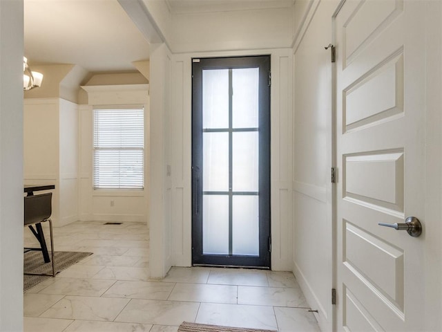 doorway to outside with marble finish floor, visible vents, a decorative wall, and an inviting chandelier