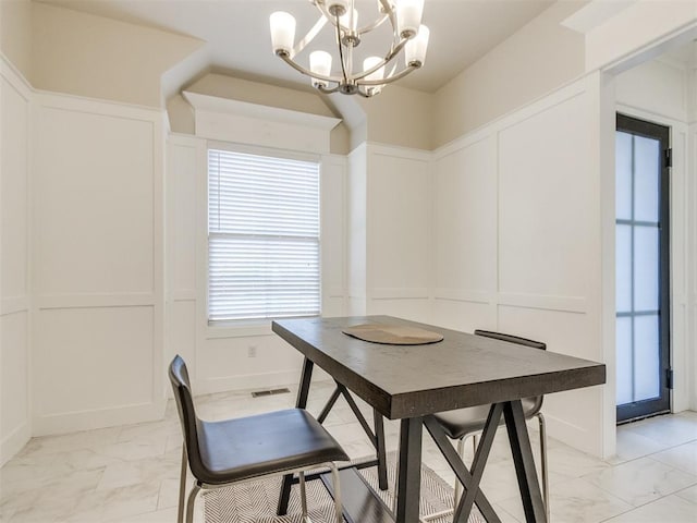 dining room featuring marble finish floor, visible vents, a decorative wall, and an inviting chandelier