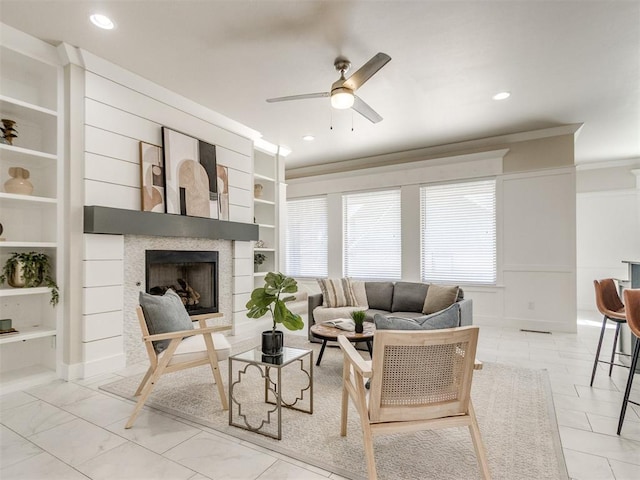 living room featuring built in features, a fireplace, recessed lighting, ornamental molding, and ceiling fan