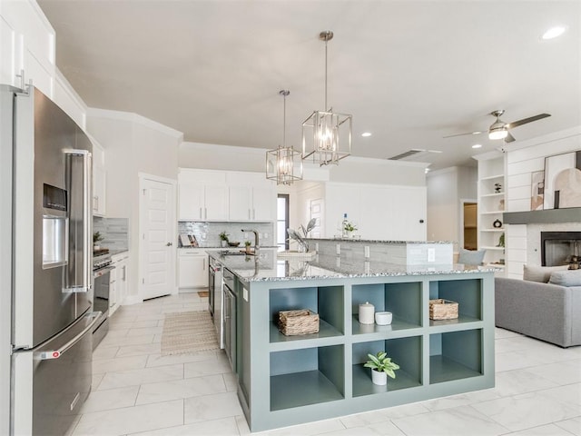 kitchen with appliances with stainless steel finishes, white cabinets, hanging light fixtures, and a large island