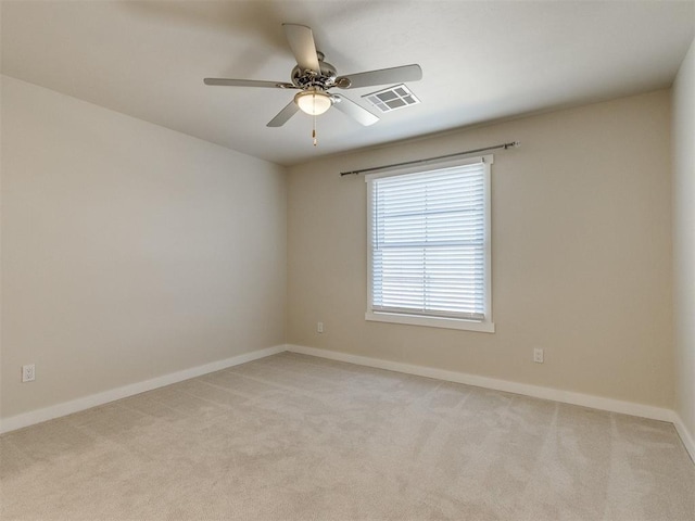 spare room featuring baseboards, ceiling fan, visible vents, and light colored carpet