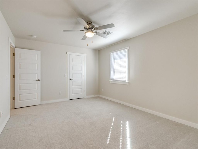 unfurnished room with a ceiling fan, visible vents, light carpet, and baseboards