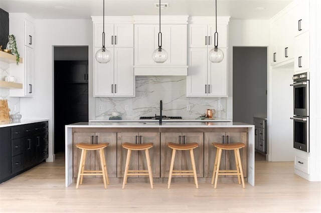 kitchen with decorative light fixtures, stainless steel double oven, and white cabinetry