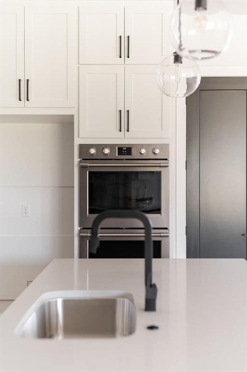 interior space with sink, white cabinets, and stainless steel double oven