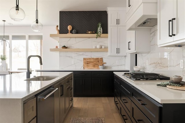 kitchen with white cabinets, custom exhaust hood, sink, and hanging light fixtures