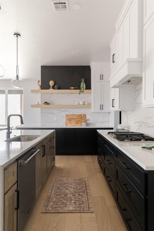 kitchen featuring white cabinets, sink, hanging light fixtures, light wood-type flooring, and stainless steel appliances