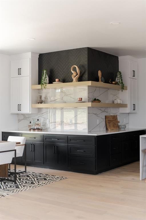 bar featuring tasteful backsplash, white cabinetry, and light hardwood / wood-style floors