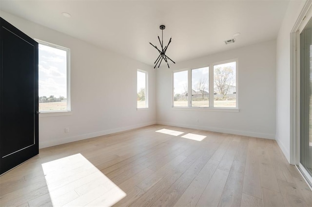 unfurnished room featuring a chandelier and light wood-type flooring