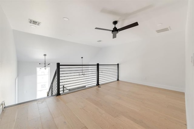 spare room with ceiling fan with notable chandelier, light wood-type flooring, and vaulted ceiling