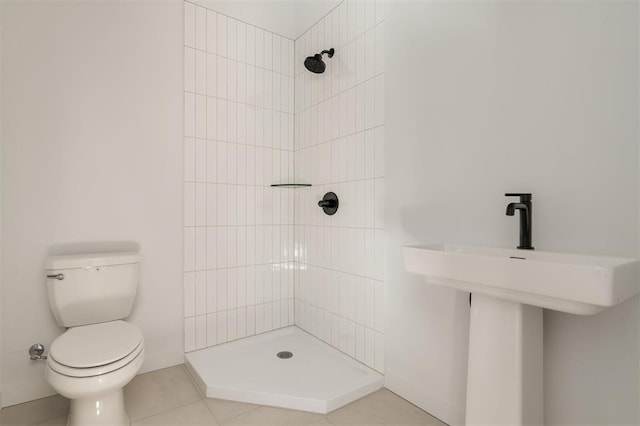 bathroom featuring toilet, tile patterned flooring, and tiled shower