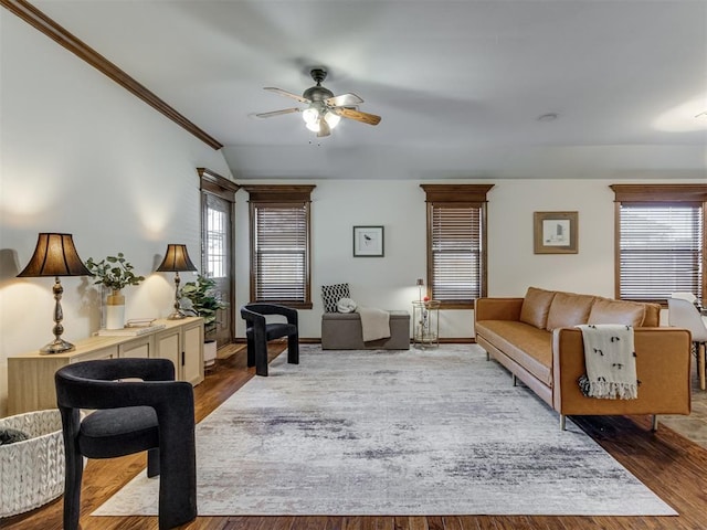 living room with wood-type flooring, vaulted ceiling, ceiling fan, and ornamental molding