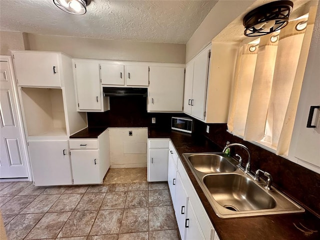 kitchen with a textured ceiling, white cabinetry, sink, and tasteful backsplash