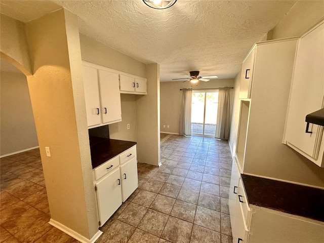 kitchen featuring tile patterned floors, a textured ceiling, white cabinetry, and ceiling fan