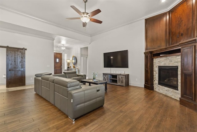 living room with dark hardwood / wood-style floors, a stone fireplace, ceiling fan, and ornamental molding