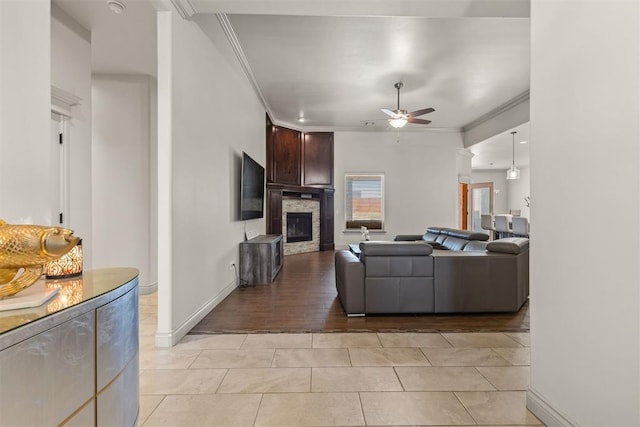 living room featuring ceiling fan, a fireplace, light hardwood / wood-style floors, and ornamental molding