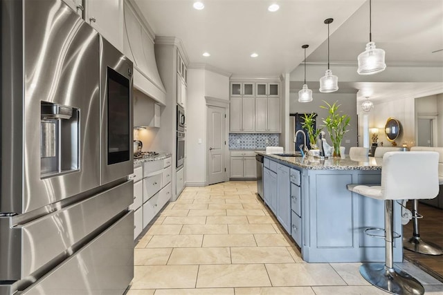 kitchen with pendant lighting, light stone counters, sink, and appliances with stainless steel finishes