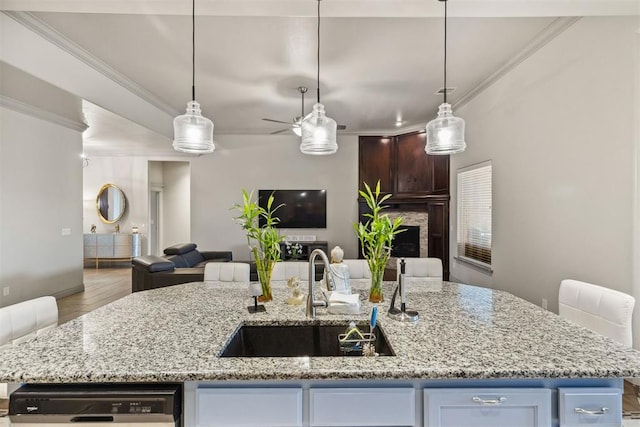 kitchen featuring a center island with sink, decorative light fixtures, light wood-type flooring, and sink