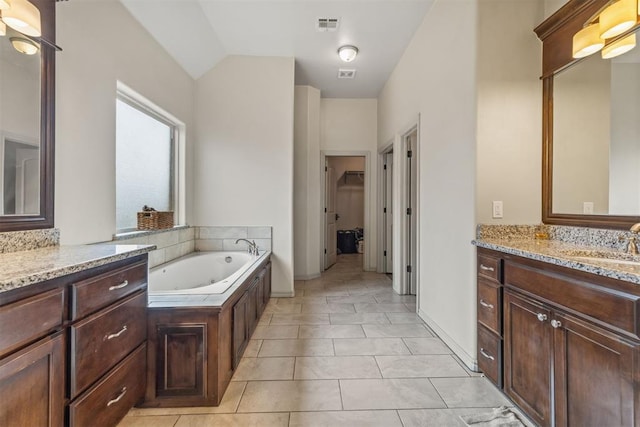 bathroom with tile patterned floors, a bathtub, vanity, and vaulted ceiling