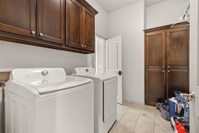 laundry room featuring washer and clothes dryer, cabinets, and light tile patterned floors