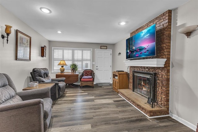 living room with dark wood-type flooring and a brick fireplace