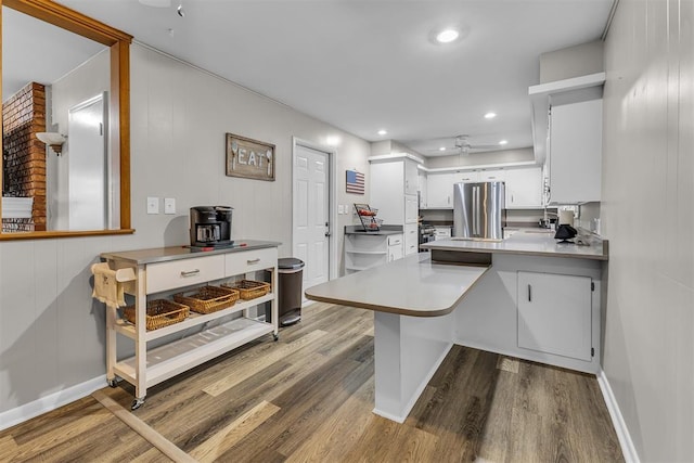 kitchen featuring kitchen peninsula, stainless steel fridge, ceiling fan, hardwood / wood-style flooring, and white cabinetry