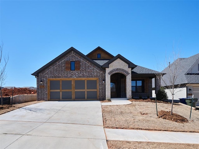 view of front of property with a garage, driveway, brick siding, and roof with shingles