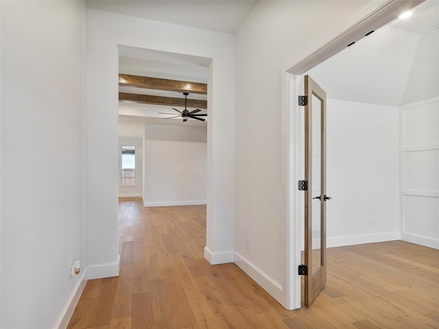 corridor with beamed ceiling, light wood-style flooring, and baseboards