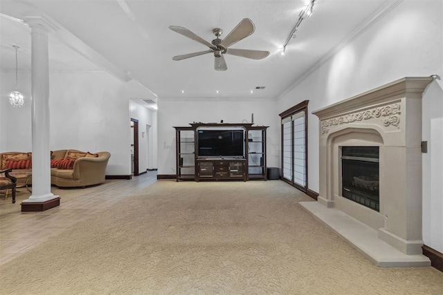 carpeted living room featuring ornate columns, crown molding, track lighting, and ceiling fan with notable chandelier